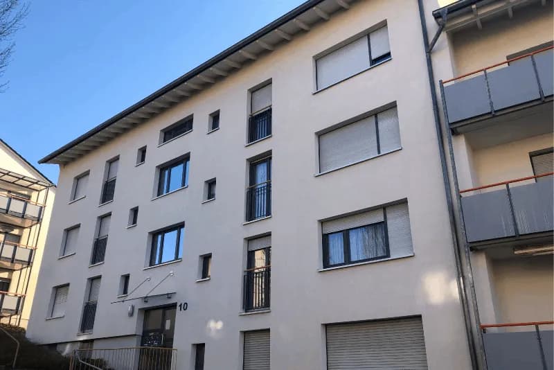 Gereinigte helle Putzfassade eines viergeschossigen Mehrfamilienhauses nach der Fassadenreinigung